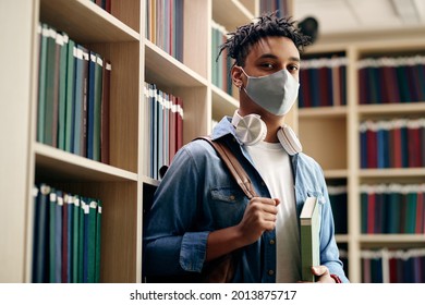 Portrait Of African American University Student Wearing Face Mask In A Library During Coronavirus Pandemic.