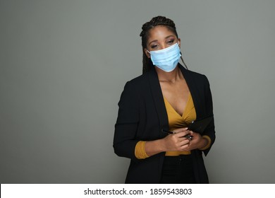 Portrait Of An African American Woman In Business Suit Wearing Face Mask Isolated On Gray Copy Space