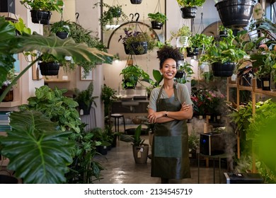 Portrait of african american woman with crossed arms wearing apron in botanical store. Happy small business owner working at flower shop standing surrounded by plants while looking at camera. - Powered by Shutterstock