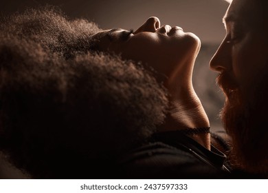 portrait of african american woman with curly hair seducing bearded man with red hair, sexy couple