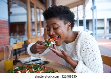 Portrait Of An African American Woman Eating Pizza At Outdoor Restaurant