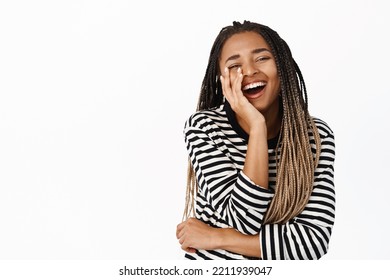 Portrait Of African American Woman Laughing And Smiling, Touching Her Face, Expressing Genuine Happiness And Joy, Standing Over White Background