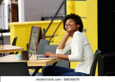 Portrait Of An African American Woman Laughing With Laptop At Cafe