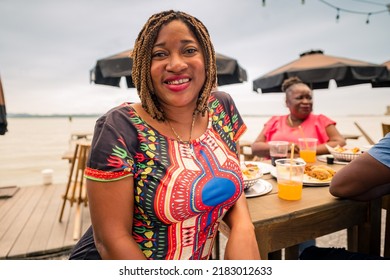 Portrait Of An African American Woman Looking At The Camera. Garifuna Woman Hanging Out With Her Family Or Friends At A Beach Restaurant.