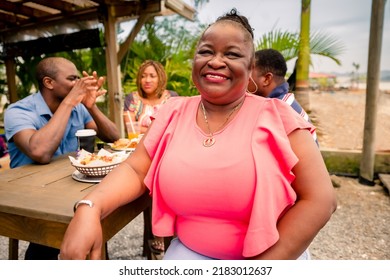 Portrait Of An African American Woman Looking At The Camera. Garifuna Woman Hanging Out With Her Family Or Friends At A Beach Restaurant.