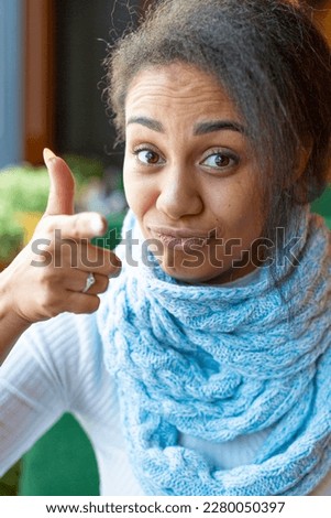 Portrait of an African American woman making a video call. She points her finger at you. Close-up picture.