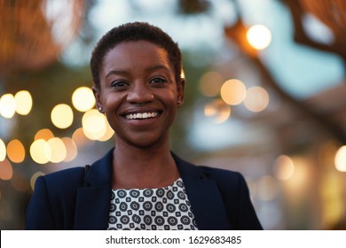 Portrait african american woman smiling confident female in city evening with lights in background