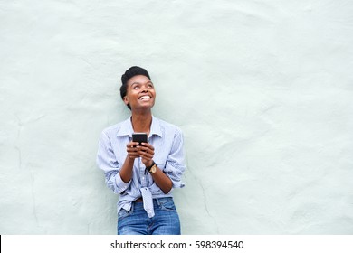 Portrait of african american woman smiling with mobile phone and looking up
