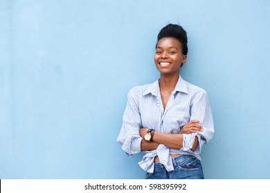 Portrait Of African American Woman Smiling With Arms Crossed On Blue Background