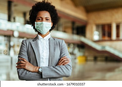 Portrait Of African American Woman Wearing Protective Mask While Standing With Arms Crossed At The Airport During Virus Epidemic. 