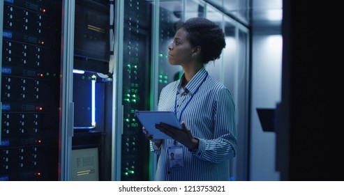 Portrait Of African American Woman Working As IT Engineer And Standing Among Server Racks In Data Center Room