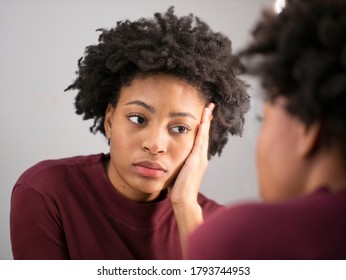 Portrait african american women looking mirrorr concerned skin and appearance.