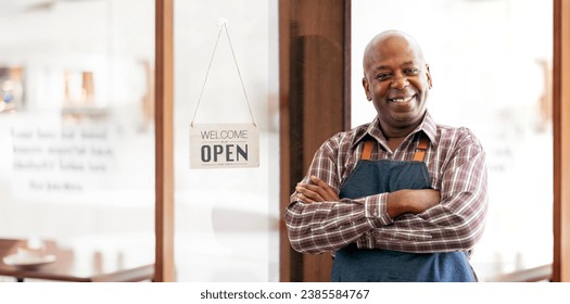 Portrait African barista or waiter cafe or coffee shop owner against entrance with open signboard, smiling guy in apron standing outdoors being proud of his small local business - Powered by Shutterstock