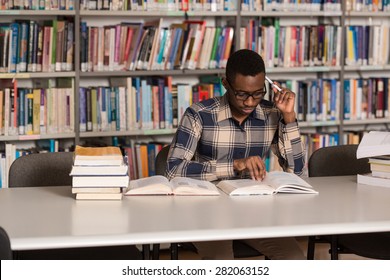 Portrait Of African Clever Student With Open Book Reading It In College Library - Shallow Depth Of Field