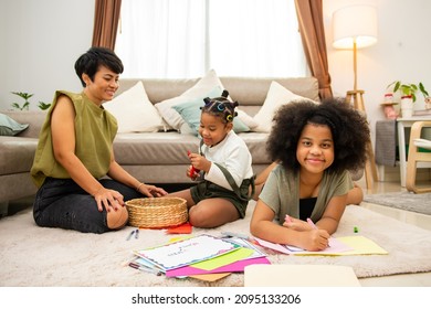 Portrait Of African Family Mother And Two Little Daughter Sit On The Floor Using Color Pencil Drawing And Painting On Paper. Mom With Child Girl Kid Enjoy And Having Fun Homeschooling Together At Home