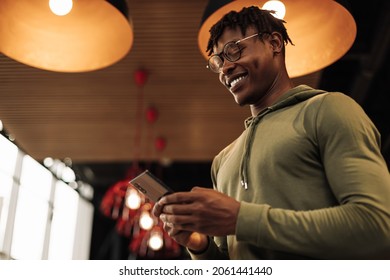 portrait African man with a phone in his hands prints a message in the office. a man with a teleophone in his hands, in a room at home. online shopping, looking for where to go to travel - Powered by Shutterstock