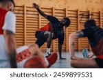 Portrait of an african man professional basketball team member stretching and warming up before training in a sports hall. Health, wellness and game start. Black male player preparing for a match.