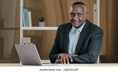 Portrait of African mature senior old businessman sitting in office at table with laptop nodding head answering yes approval supporting good idea agree reaction positive choice decision
