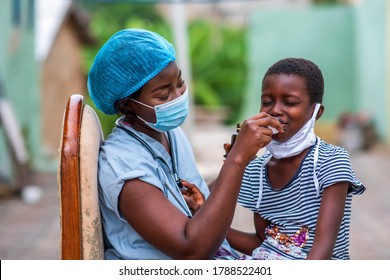 Portrait Of An African Nurse Administering Drug To A Child In Homemade Mask In Covid-19 Pandemic-concept On Millennial Health Workers Child Health And Vaccination In Corona Virus Pandemic