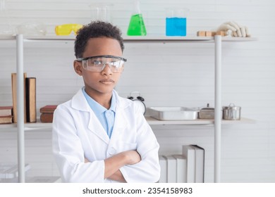 Portrait of African student in lab coat uniform arm crossed wearing safety eyeglass in laboratory, cute boy in science classroom, primary school pupil kid scientist or specialist doctor career concept - Powered by Shutterstock