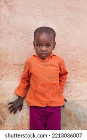 Portrait Of African Village Girl, Standing In The Yard Next To A Wall