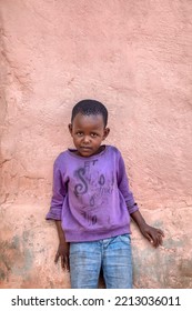 Portrait Of African Village Girl, Standing In The Yard Next To A Wall