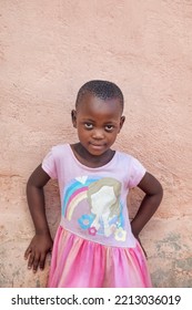 Portrait Of African Village Girl, Standing In The Yard Next To A Wall