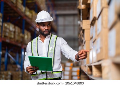 Portrait of an African warehouse manager holding a clipboard checking inventory in a large distribution center. - Shutterstock ID 2061048803