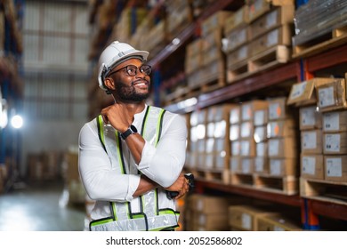 Portrait Of An African Warehouse Manager Standing In A Large Distribution Center Holding Barcode Reader.