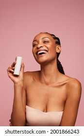 Portrait Of African Woman Holding A Skincare Product And Smiling. Attractive Woman With Beautiful Skin Holding A Cosmetic Cream Bottle.