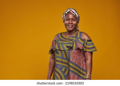 Portrait of African woman in national costume smiling at camera isolated on yellow background