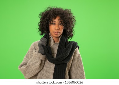 Portrait Of African Woman Wearing Winter Wear On Green Screen. Cold Woman Dressed In Sweater And Scarf