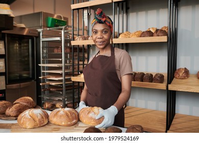 Portrait of African young baker in uniform baking a fresh bread in the bakery