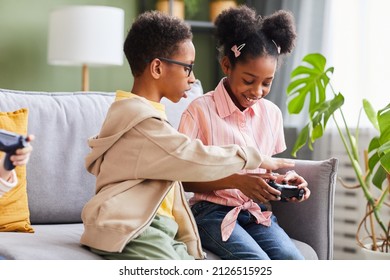 Portrait of African-American brother and sister playing video games at home together - Powered by Shutterstock