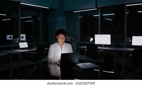 Portrait of African-American businesswoman typing on laptop and smiling working late in dark office. Female entrepreneur overwork at night - Powered by Shutterstock