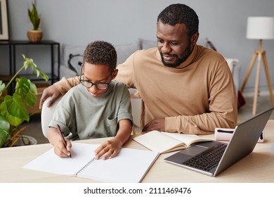 Portrait of African-American father helping son with homeschooling while studying at home, copy space - Powered by Shutterstock