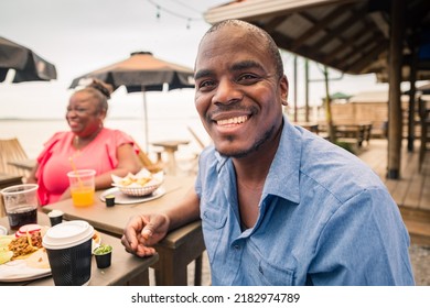 Portrait Of An African-American Man Hanging Out With His Family Or Friends At A Beach Restaurant.