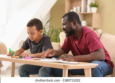 Portrait African  American man   his little son drawing at home
