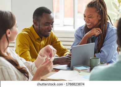 Portrait of African-American man and woman laughing cheerfully while working on team project with multi-ethnic group of people, copy space