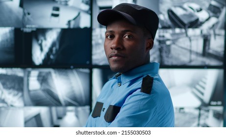 Portrait of African-American security officer looking at camera standing in control room with multiple screens with life cctv footage on background - Powered by Shutterstock