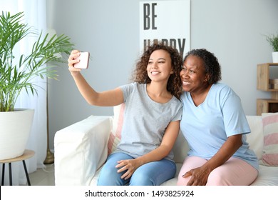 Portrait of African-American woman with her daughter taking selfie at home