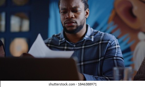 Portrait von afro Geschäftsmann suchen Dokumente in der Zusammenarbeit. Nahaufnahme verärgerter afrikanischer Profi-Krümelpapier im Kreativbüro. enttäuschter afrikanischer Kerl wirft Papier ins Büro