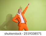 Portrait of aged man performer point finger up empty space wear orange suit isolated on green color background