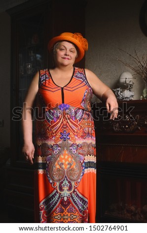 Portrait of an aged woman.  Overweight grandmother wearing a colorful dress and a funny hat.