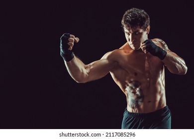 Portrait of aggressive boxer training and practicing uppercut. Isolated on black studio background. Concept of sport, healthy lifestyle. 