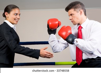 Portrait of aggressive businessman in boxing gloves fighting with positive female with her arm stretched for handshake - Powered by Shutterstock