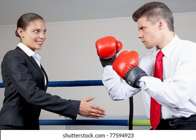 Portrait of aggressive businessman in boxing gloves fighting with positive female with her arm stretched for handshake - Powered by Shutterstock