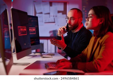 Portrait of agitated cybersecurity team working in emergency mode with critical error message on computer screen - Powered by Shutterstock