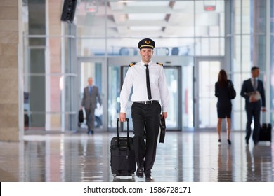 Portrait Of Airline Pilot Walking Through Airport Lounge