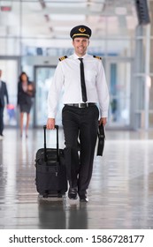 Portrait Of Airline Pilot Walking Through Airport Lounge